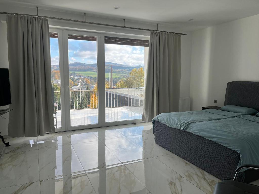 een slaapkamer met een bed en uitzicht op een balkon bij Hamdanes Apartment in Sundern