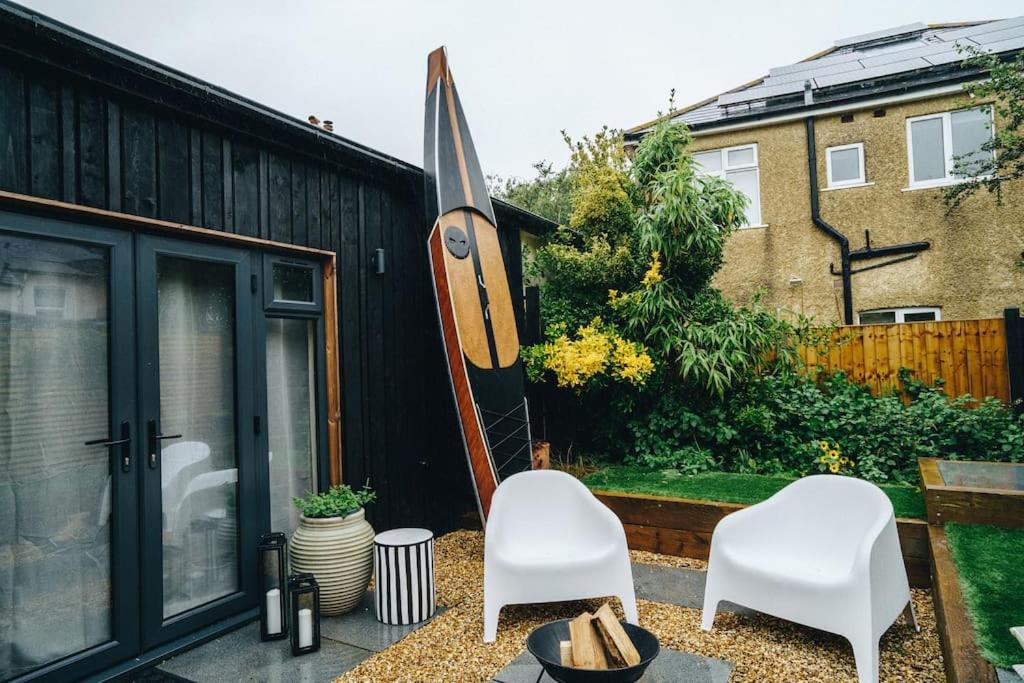 un patio con 2 sillas blancas y una tabla de surf en The Cabin - Close to the beach - Entire Place - Raised Bed, en Bournemouth