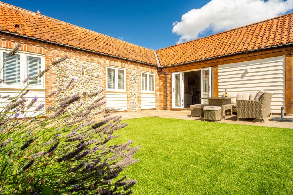 a garden with a lawn and a house at Filby Barn by Big Skies Cottages in Docking