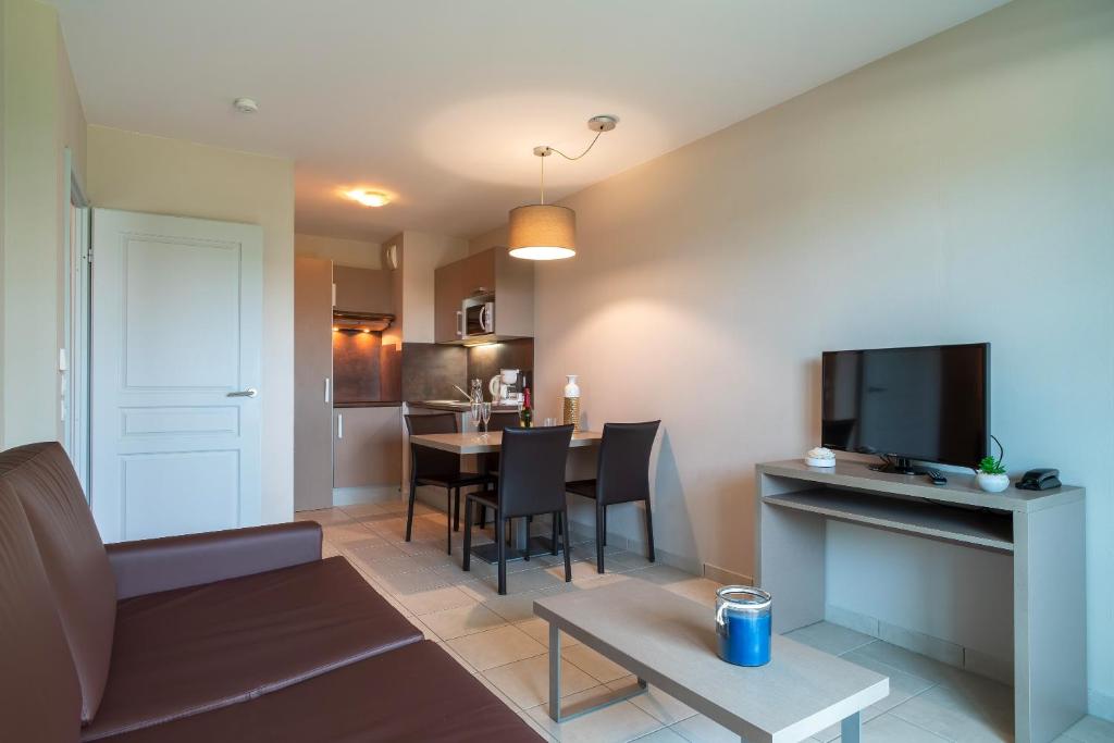 un salon avec un canapé et une table avec une télévision dans l'établissement Les Thermes 404 - Appt proche plage avec piscine partagée, à Concarneau