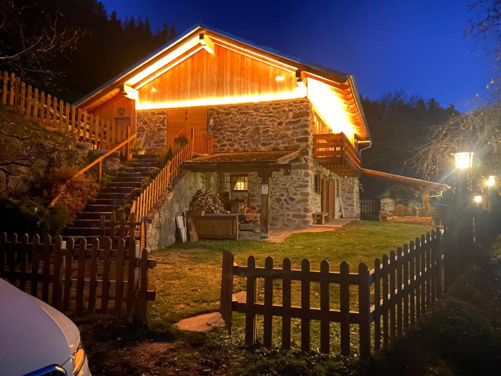 une maison en pierre avec une clôture en bois devant elle dans l'établissement Baita del Beniamino, à Roncegno