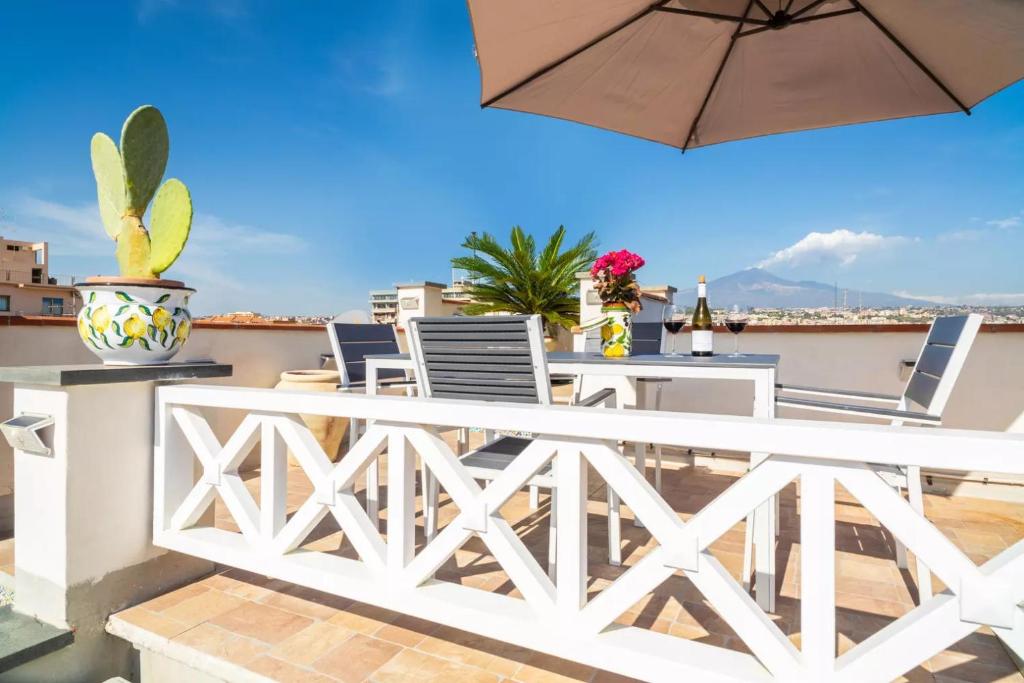 une terrasse avec une table, des chaises et un parasol dans l'établissement La terrazza sul cielo, à Catane