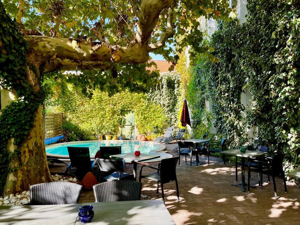 un patio con tavoli, sedie e piscina di CitHôtel Le Louvre a Orange