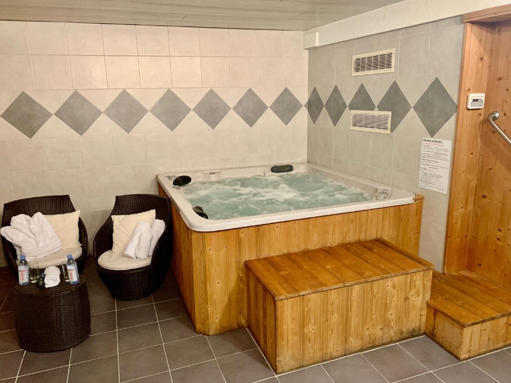 莫爾濟訥的住宿－Hameau des Prodains - Hôtel，一个带两把椅子的房间的热水浴缸