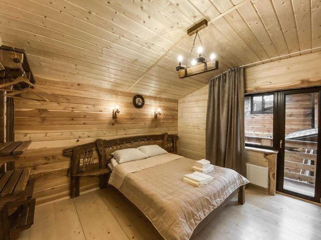 een slaapkamer met een bed in een houten hut bij Adel Resort in Plavie