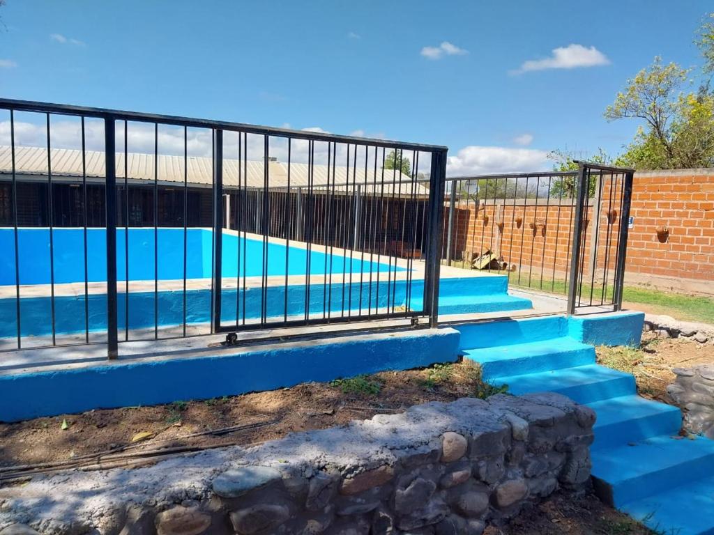 a swimming pool with blue stairs next to a fence at Cabañas Las Delicias in Salta
