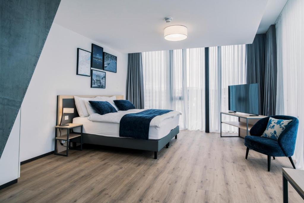 a bedroom with a bed and a tv and a chair at YParc Hôtel in Yverdon-les-Bains