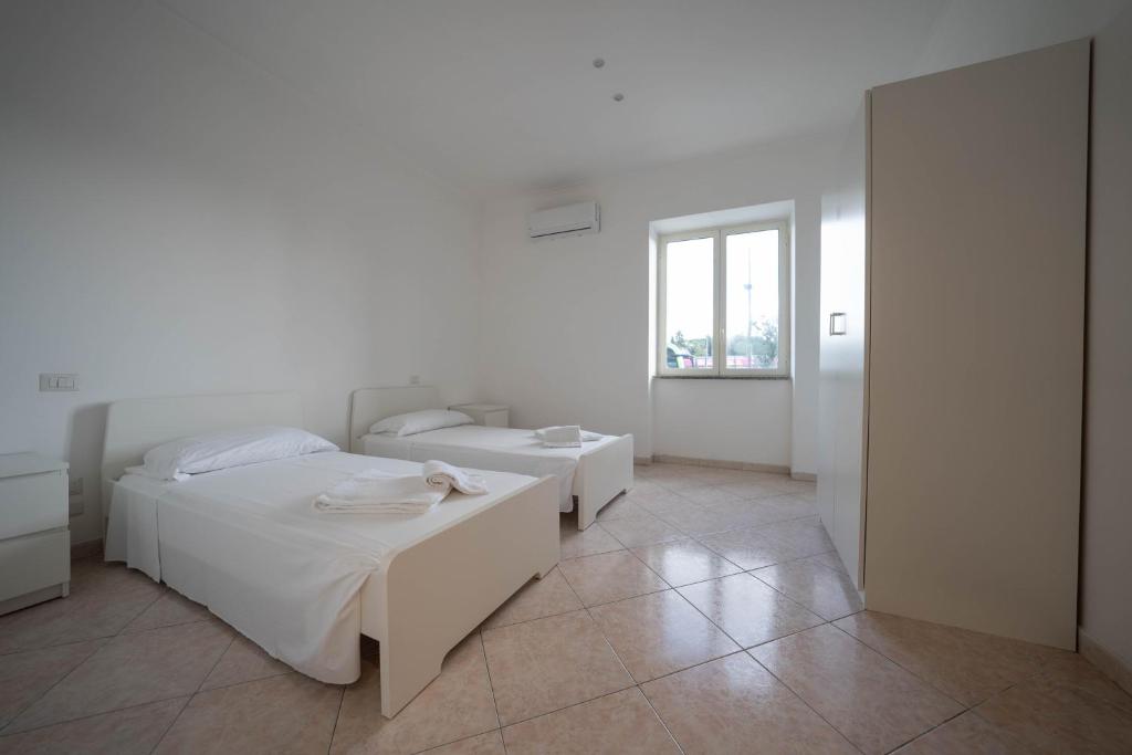 a white bedroom with two beds and a window at Capodichino Airport Home By Dimorra in Naples