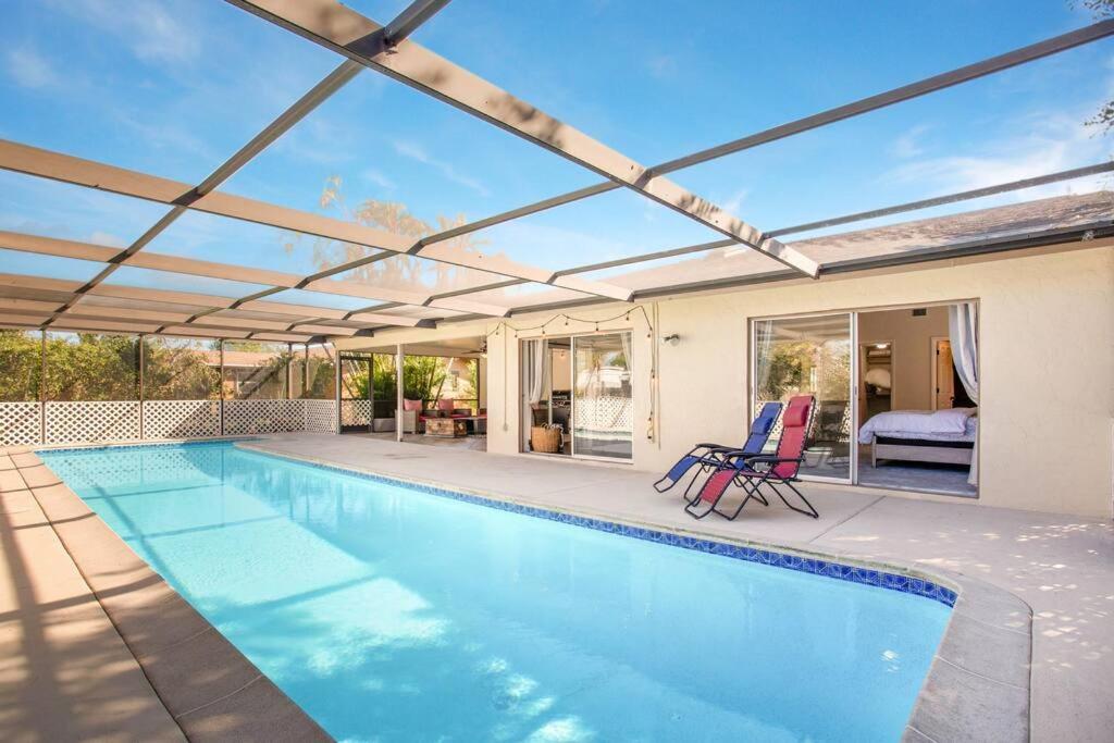 a swimming pool with two chairs next to a house at Naples Oasis in Naples