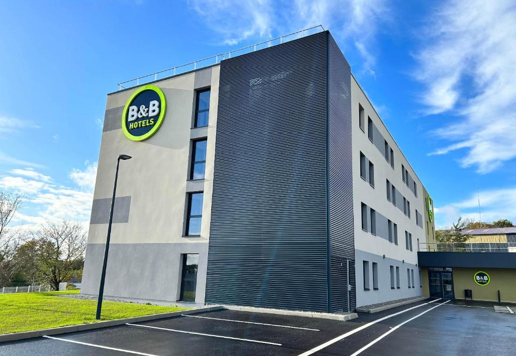 un bâtiment avec un panneau sur son côté dans l'établissement B&B HOTEL Besançon Valentin, à Besançon