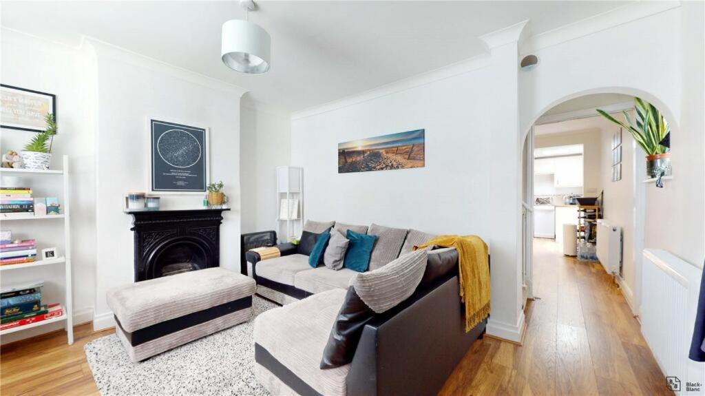 een woonkamer met een bank en een open haard bij Charming 2-Bedroom Flat in the Heart of Cro London ER1 in South Norwood