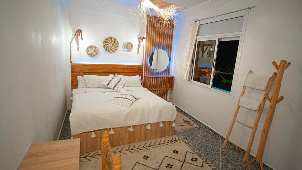 1 dormitorio con cama, ventana y silla en Paddle Out Morocco en Tamraght Ouzdar