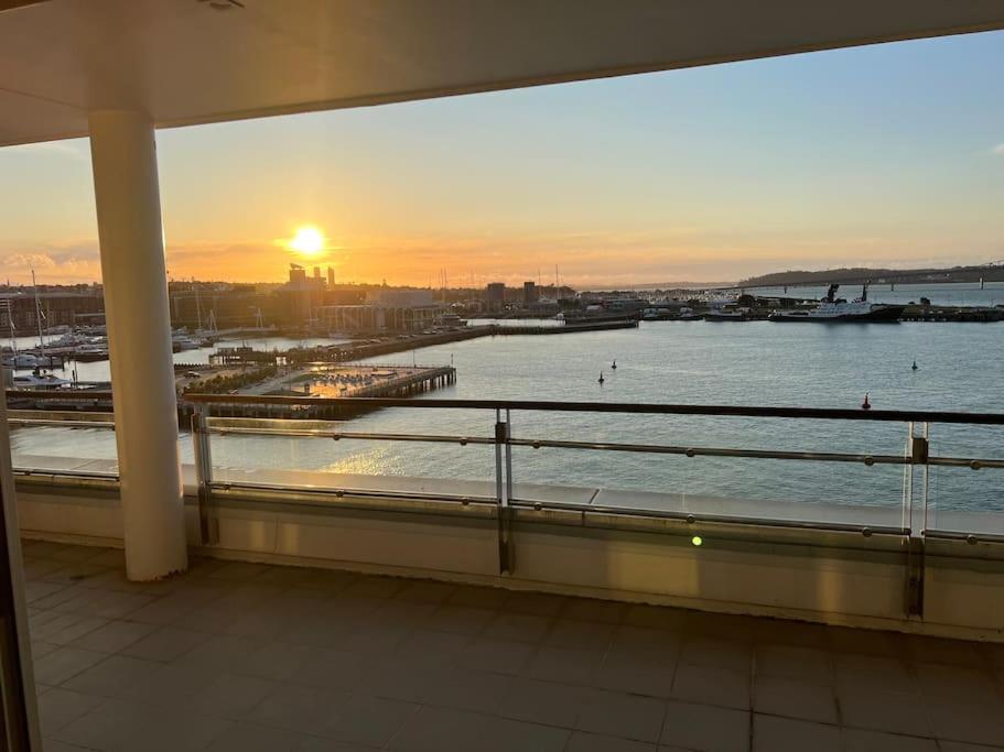 een balkon met uitzicht op het water bij zonsondergang bij Waterfront Seaview Hotel Apartment - same building block as Auckland Hilton in Auckland