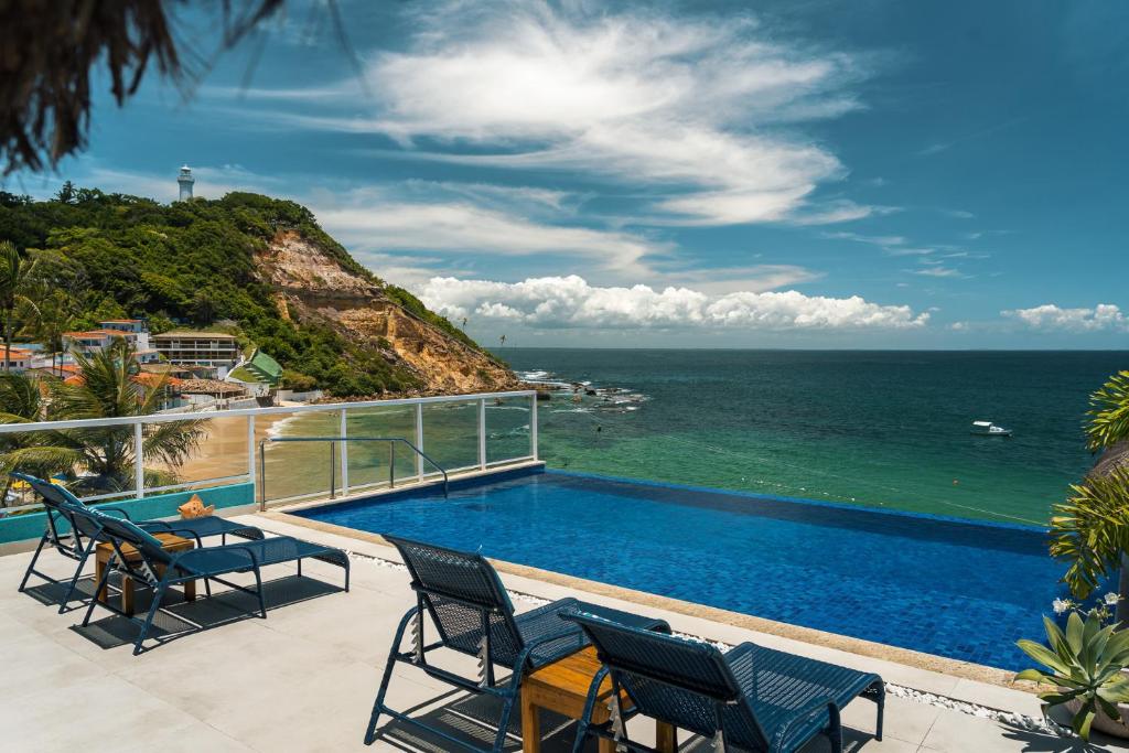 a balcony with a swimming pool and the ocean at Pousada Dona Moça in Morro de São Paulo