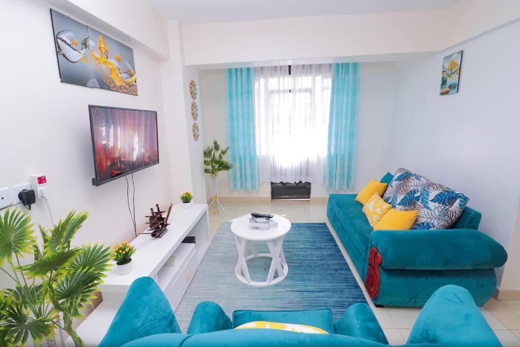 a living room with a blue couch and a table at LaMeg furnished 1 bedroom Garden Estate in Nairobi