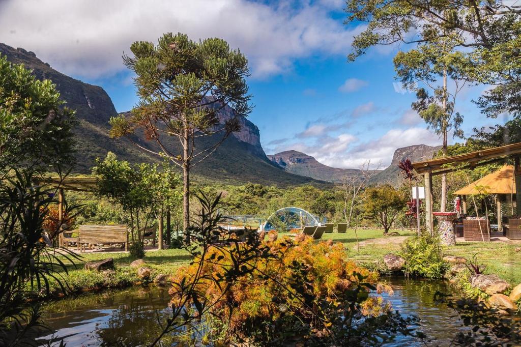 einen Garten mit einem Fluss und Bergen im Hintergrund in der Unterkunft Pousada do Capão Chapada Diamantina in Vale do Capao