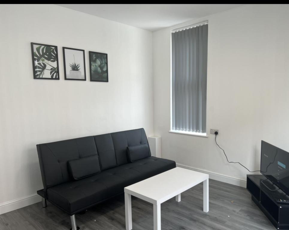 sala de estar con sofá negro y mesa en ASM London Road Studio Apartments, en Leicester