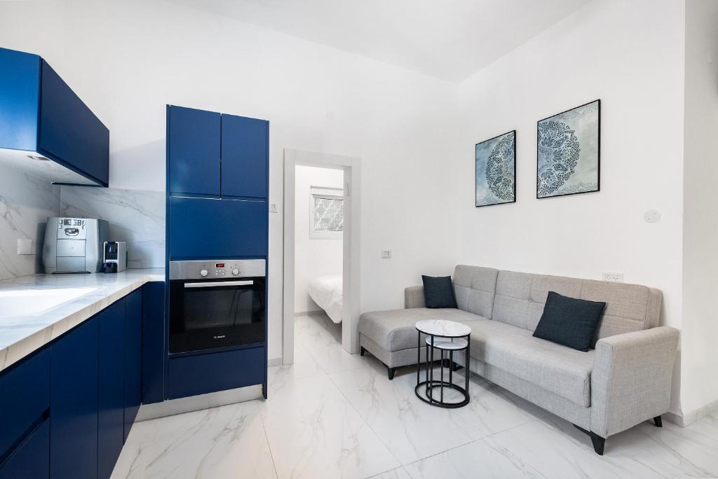 een keuken en een woonkamer met een bank en een tafel bij Moroccan style apartment near Bahai Gardens in Haifa