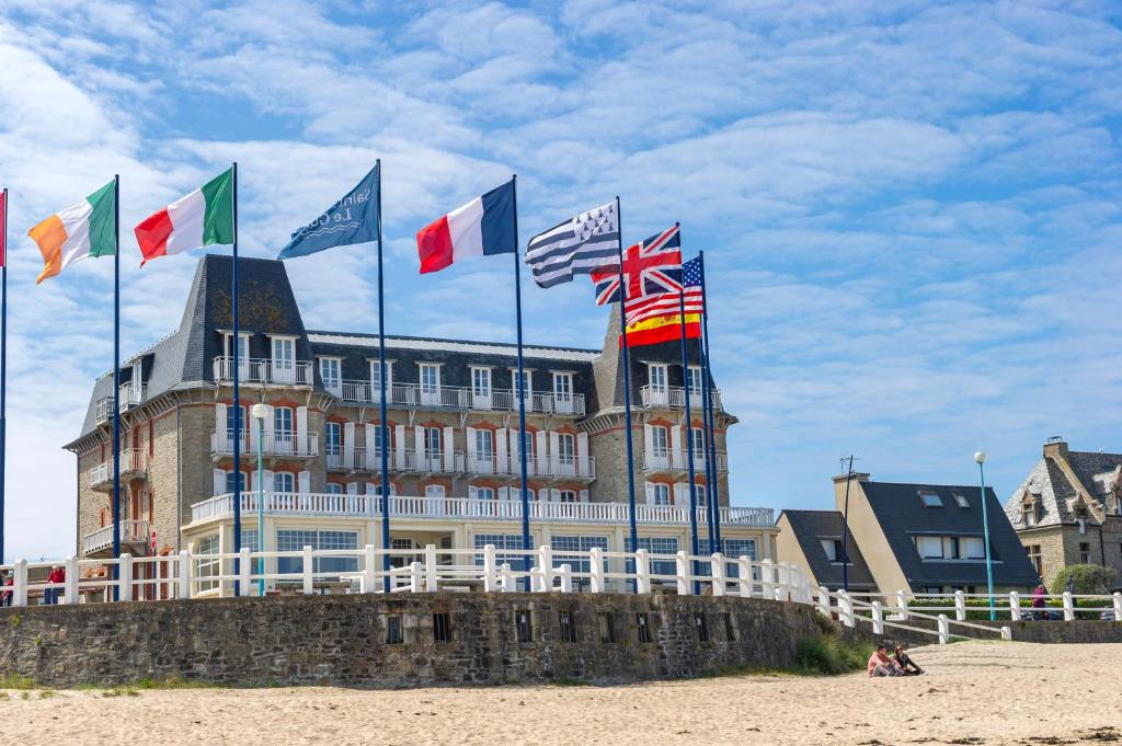 VTF L'Hotel Des Bains في سانت كاست-لو-غيلدو: مجموعة من الأعلام على مبنى على الشاطئ