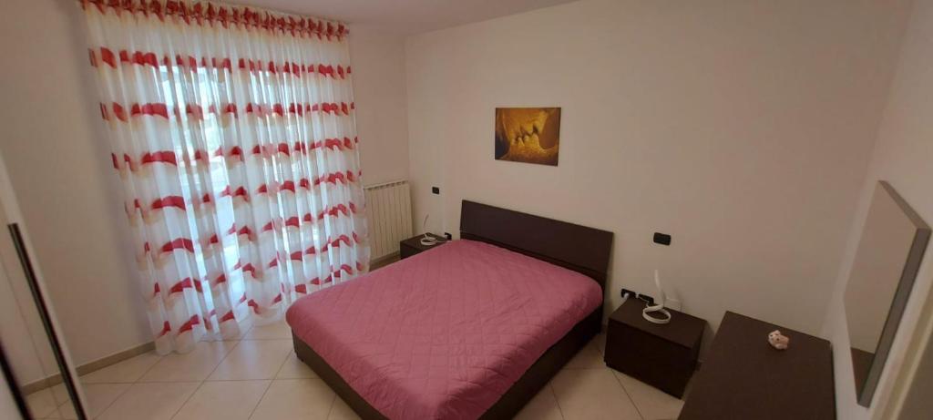 um pequeno quarto com uma cama rosa e uma janela em Casa vacanze Margherita em Barletta