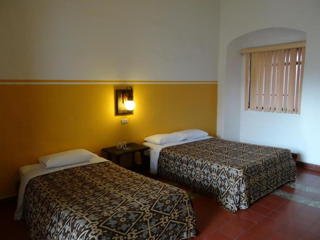 une chambre d'hôtel avec deux lits et une fenêtre dans l'établissement Hotel Principal, à Oaxaca