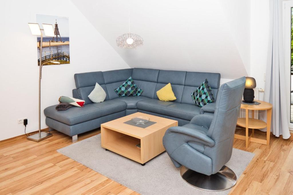 uma sala de estar com um sofá azul e uma mesa em Dallacker 8, FeWo 3 em Duhnen