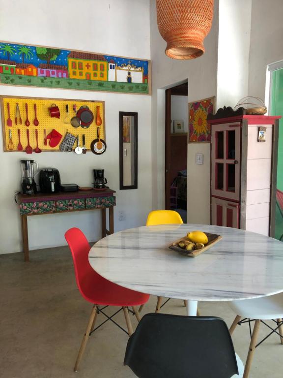 a dining room with a table and chairs with a plate of fruit at Casa Pintassilgo mini in Santa Cruz Cabrália