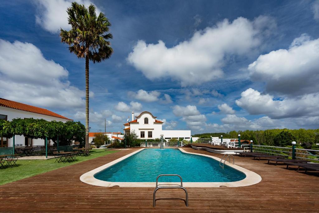 a swimming pool with a palm tree and a building at Quinta d'Anta- Hotel Rural in Maiorca