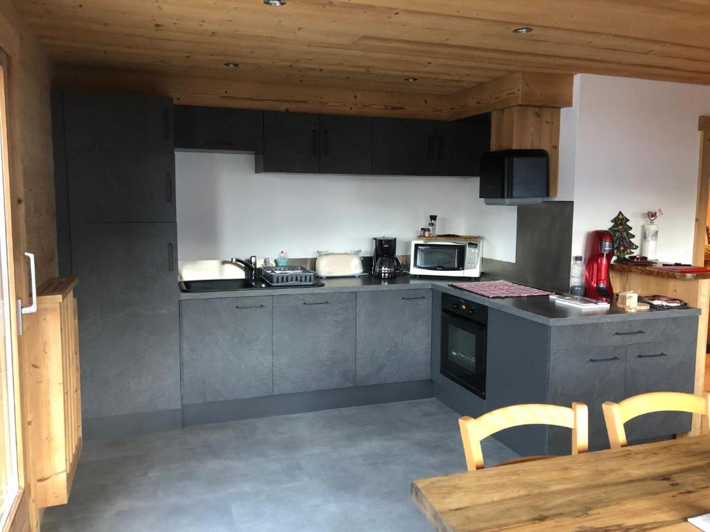 une cuisine avec une cuisinière et un micro-ondes dans l'établissement Appartement moderne 3 chambres avec balcon, près des pistes, parking et garage - FR-1-467-53, au Grand-Bornand