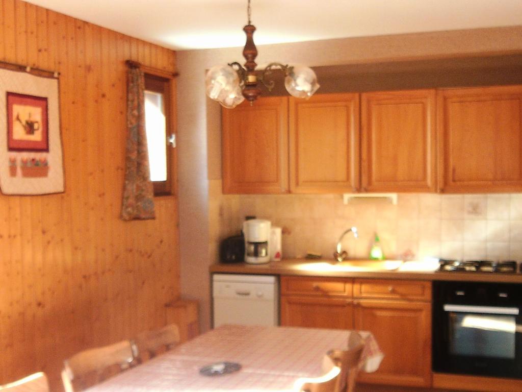 une cuisine avec des armoires en bois et une table avec des chaises dans l'établissement Appartement cosy 6 pers - proche pistes, navette, animaux admis - Grand-Bornand Village - FR-1-467-78, au Grand-Bornand