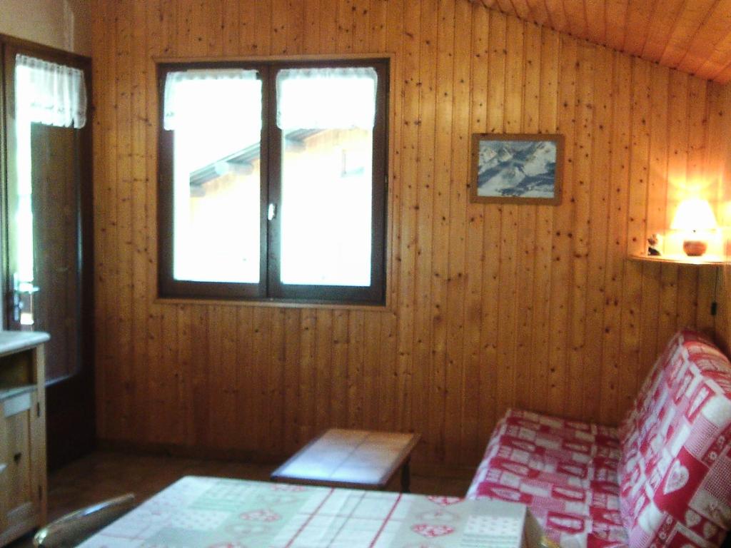 Cette chambre comprend un lit, une fenêtre et une chaise. dans l'établissement Appartement 6 pers. avec jardin, proche pistes, animaux admis, Le Grand-Bornand Village - FR-1-467-80, au Grand-Bornand