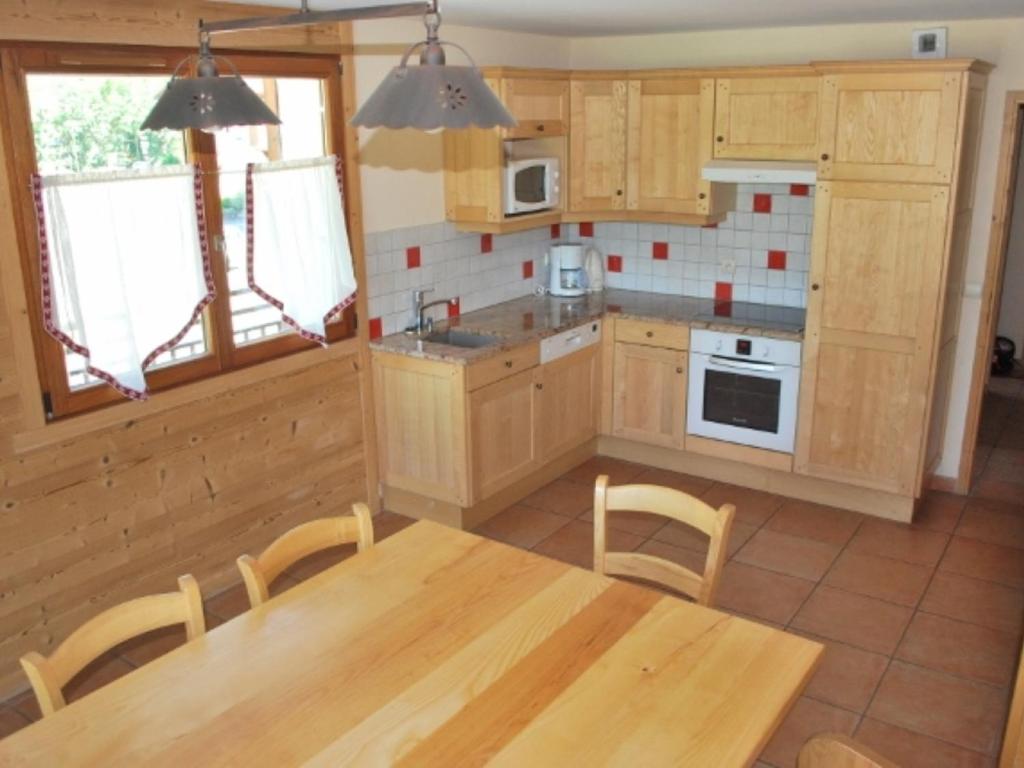 une cuisine avec des armoires en bois et une table avec des chaises dans l'établissement Appartement cosy 7 pers avec piscine, près des pistes et du centre, Le Grand-Bornand Village - FR-1-467-106, au Grand-Bornand