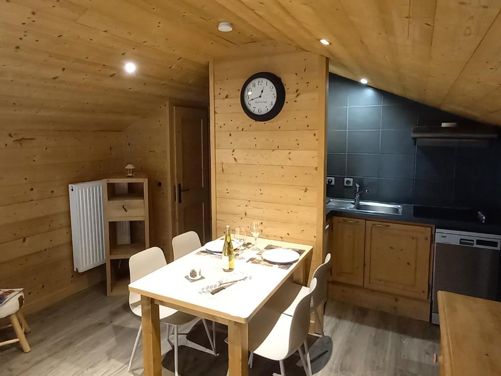 une salle à manger avec une table et une horloge murale dans l'établissement Appartement cosy avec balcon sud, proche pistes ski, animaux admis, parking privé, draps inclus - FR-1-467-113, au Grand-Bornand