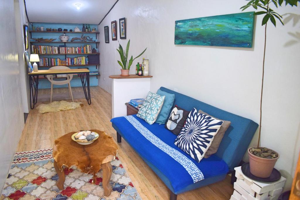 uma sala de estar com um sofá azul e uma mesa em Cozy 1-bedroom house in quiet residential village. em Iloilo