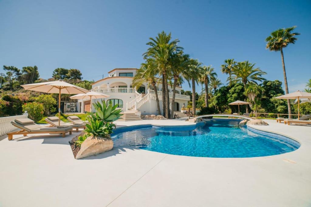 una piscina con palmeras y una casa en Villa La Palma, en Jávea