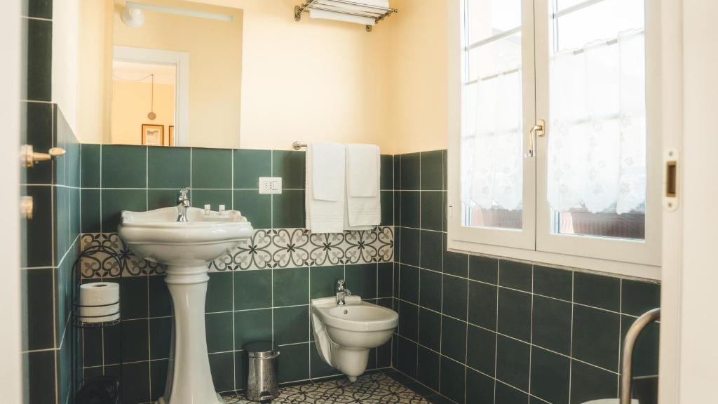un bagno piastrellato verde con lavandino e servizi igienici di Azienda agricola La Macina a Bregnano