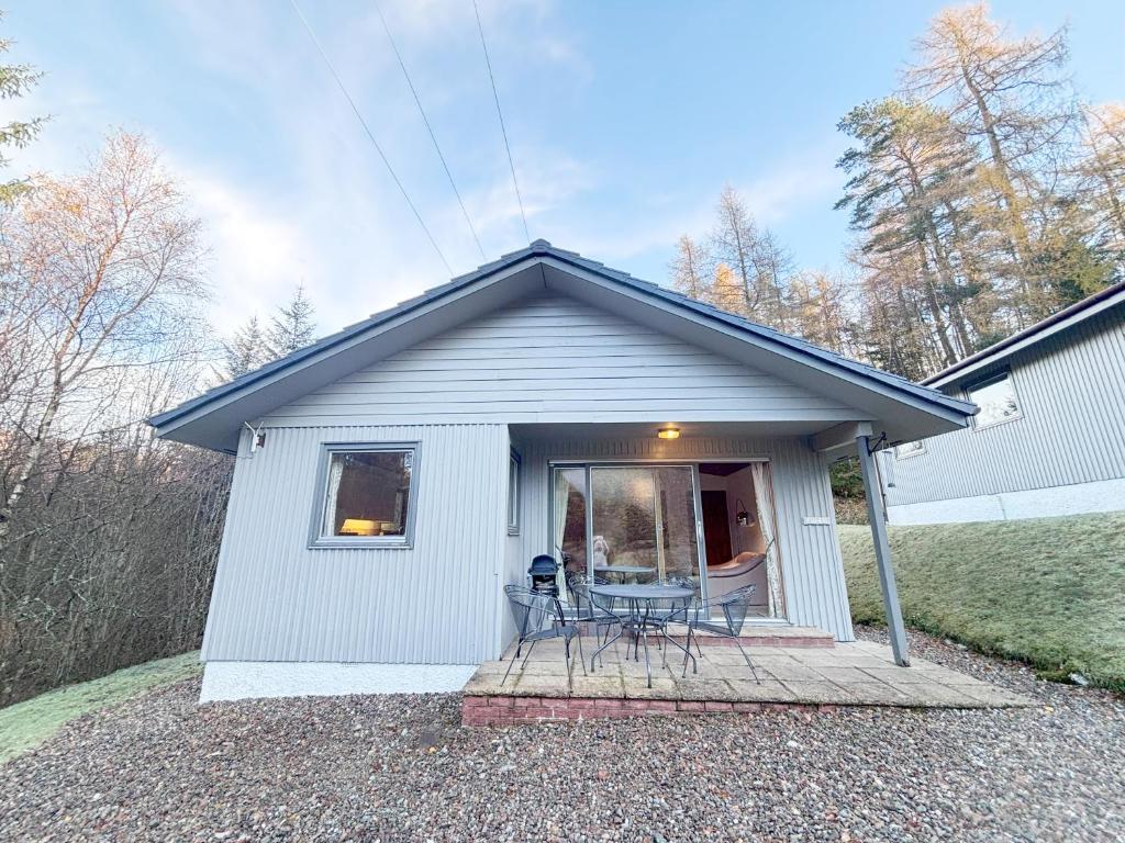 a small white house with a table and chairs at Portnellan in Crianlarich