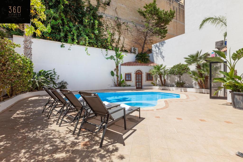 - un groupe de chaises à côté de la piscine dans l'établissement Bungalow villa with SUPER POOL AREA with WIFI & AC by 360 Estates, à San Ġiljan