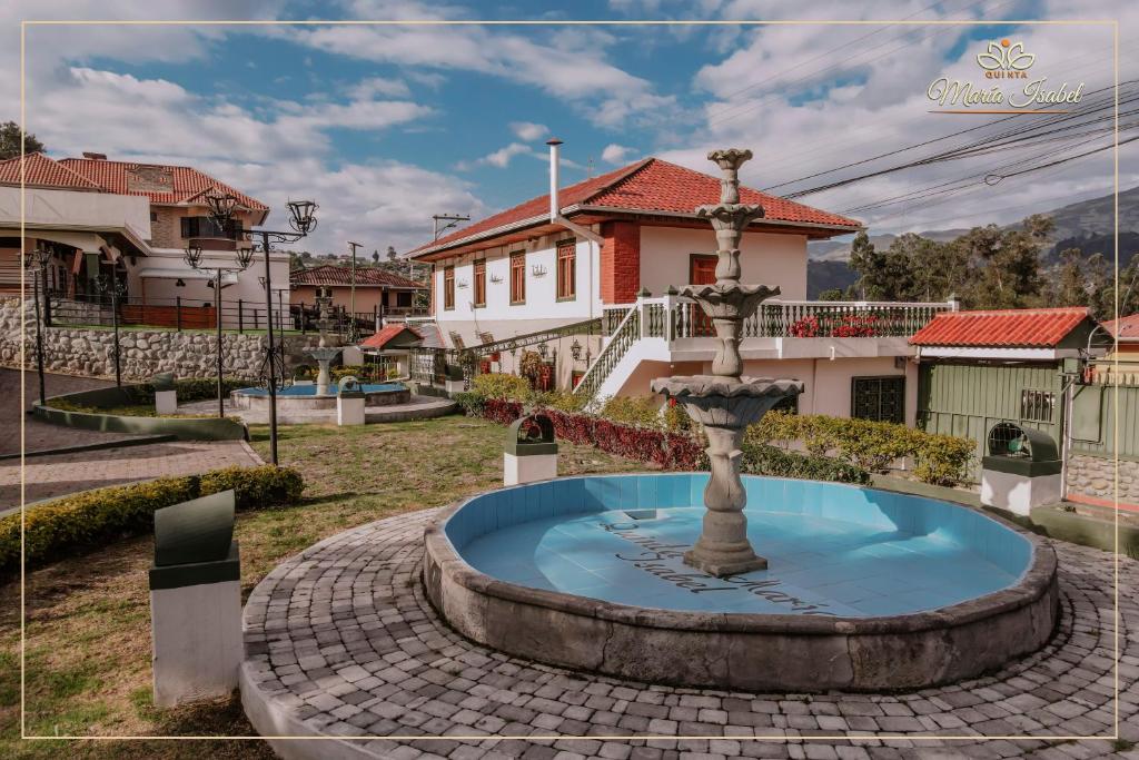 une fontaine dans une cour en face d'une maison dans l'établissement Quinta maría isabel. Elegante y restaurada, à Gualaceo