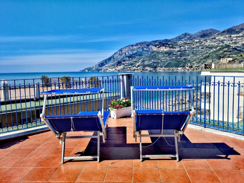 two blue chairs sitting on a balcony overlooking the ocean at A terrace on the sea in Maiori