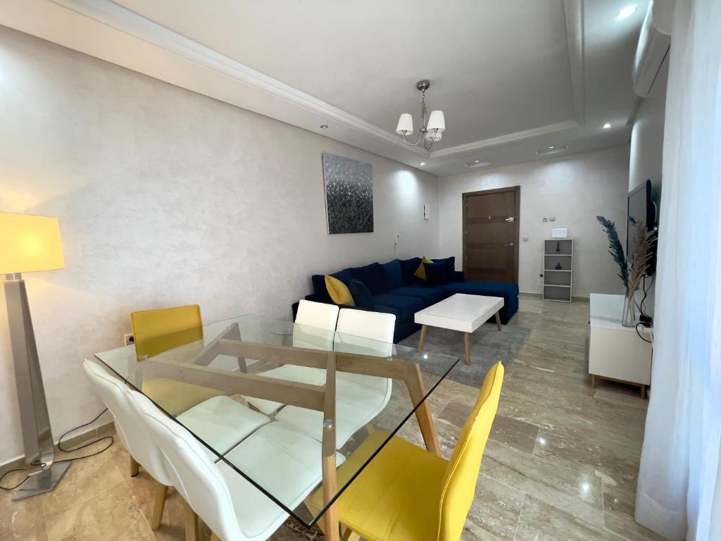 a living room with a blue couch and a glass table at Appartement Tanger Moulay Ismail in Tangier