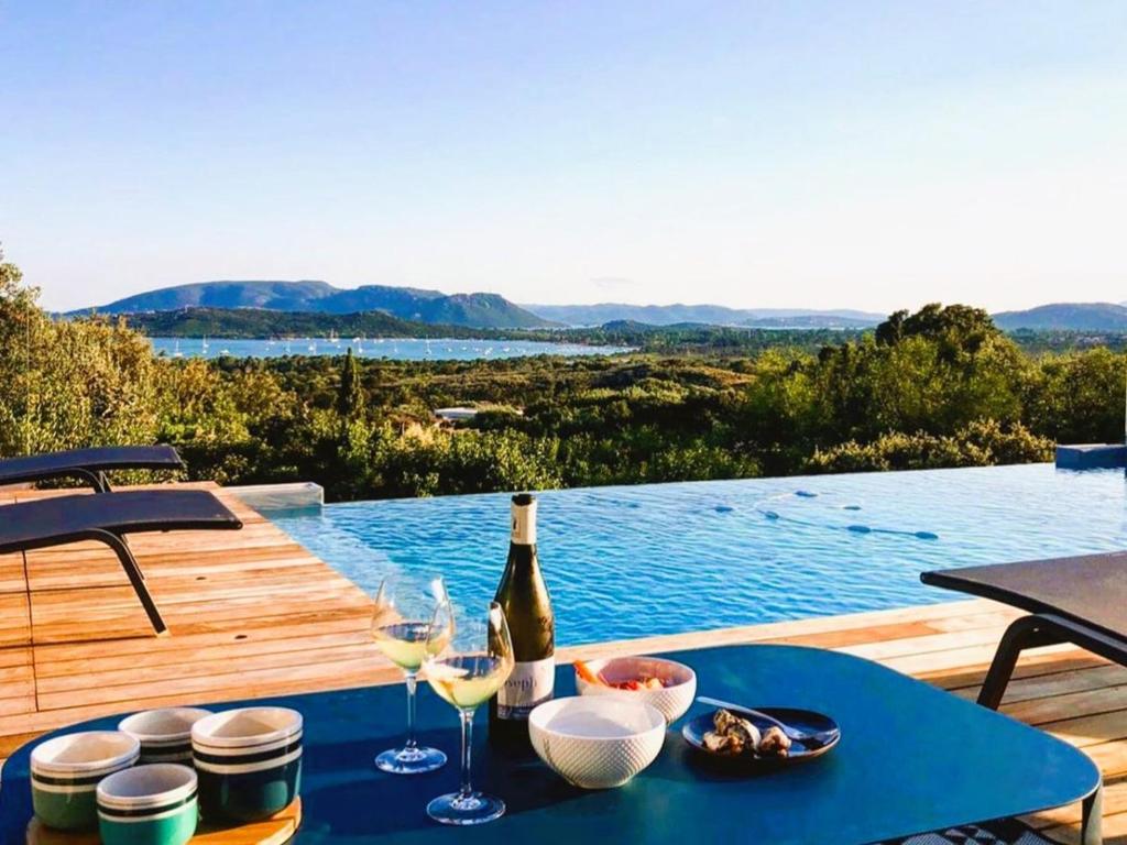 - une table avec une bouteille de vin et des verres sur une terrasse dans l'établissement Villa Arazu, 10 personnes, piscine chauffée, vue mer, 15 minutes à pieds plage, à Cirendinu