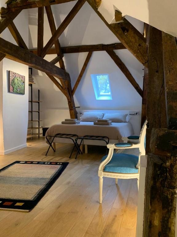 - une chambre mansardée avec un lit et deux chaises dans l'établissement galerie jacqueline storme, à Lille
