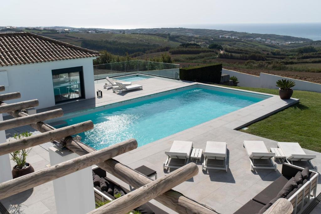 a swimming pool with chairs and a house at Casa Bica Vista Boutique B&B in Lourinhã