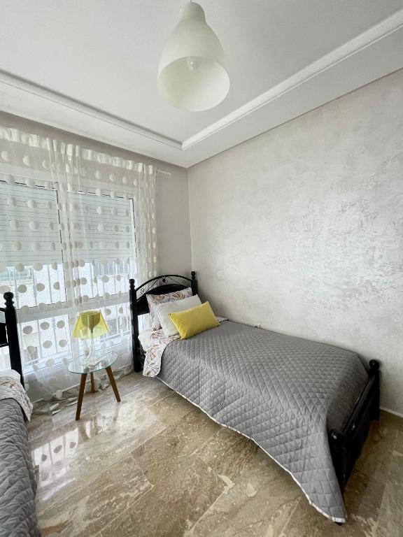 a bedroom with a bed with a yellow pillow on it at Appartement Tanger Moulay Ismail in Tangier