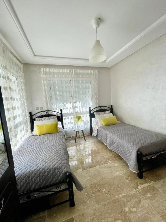 a bedroom with two beds and a window at Appartement Tanger Moulay Ismail in Tangier