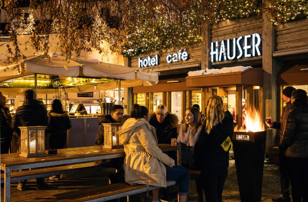 a group of people sitting at a table outside a restaurant at Hauser Hotel St. Moritz in St. Moritz