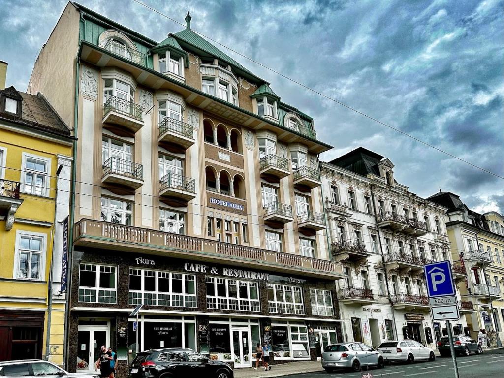 un gran edificio con coches estacionados frente a él en Hotel Aura, en Mariánské Lázně