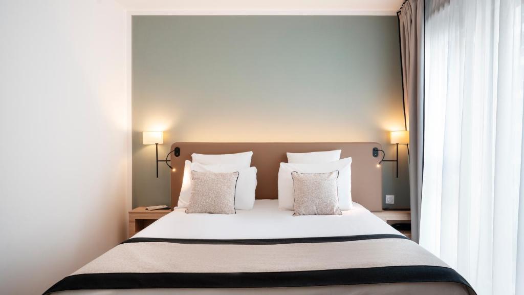 a bedroom with a bed with white sheets and pillows at Residhome Dijon Cité Des Vignes in Dijon