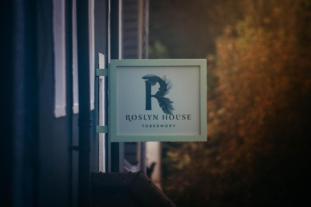 ein Zeichen für eine Rooshin-House-Technologie auf einem Gebäude in der Unterkunft Roslyn House in Tobermory